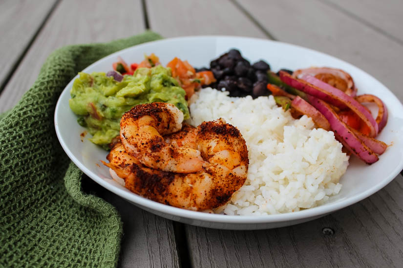 This big, bold Taco Shrimp Bowl - easily customizable to your tastes - can be on your table in under 30 minutes. Make it for Cinco de Mayo, Taco Tuesday, or a quick weeknight meal. The shrimp and veggies are cooked on a sheet pan before being served with rice, garlicky black beans and your favorite taco toppings.