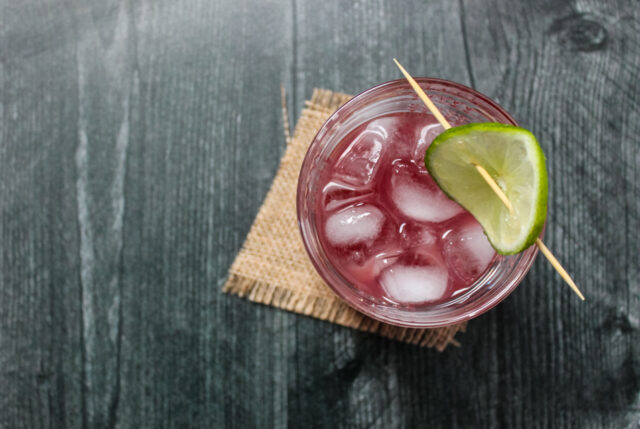 Overhead view of a pomegranate gimlet cocktail garnished with a lime wheel