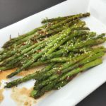 Asparagus brushed with sesame oil is grilled and then tossed with a sweet-spicy sauce and topped with toasted sesame seeds for a delicious summer side dish.