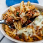 In this Baked Ziti with Sausage & Spinach, spicy Italian sausage, fresh spinach, and a tomato-pesto sauce are tossed with penne or ziti noodles for a flavorful, unique spin on the classic baked ziti recipe. Comfort food at its finest.