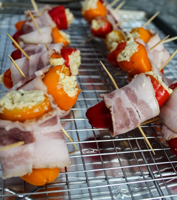 Bacon-Wrapped Cheese-Stuffed Baby Bell Peppers - Ready for the Oven -These Bacon-Wrapped Cheese-Stuffed Baby Bell Peppers were an irresistible little appetizer! Sweet baby bell peppers are stuffed with herbs and Italian cheeses and wrapped in applewood smoked bacon for a light but decadent feeling appetizer or snack.