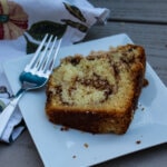 Overhead view of a slice of Sour Cream Coffee Cake with Toasted Pecan Filling, showing off the cinnamon pecan filling swirled through cake, on a small white square plate with a fork.