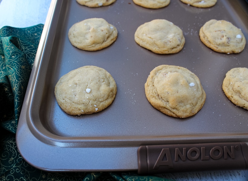 view from above, honey walnut cookies on an anolon baking sheet, sitting on top of green and gold cloth