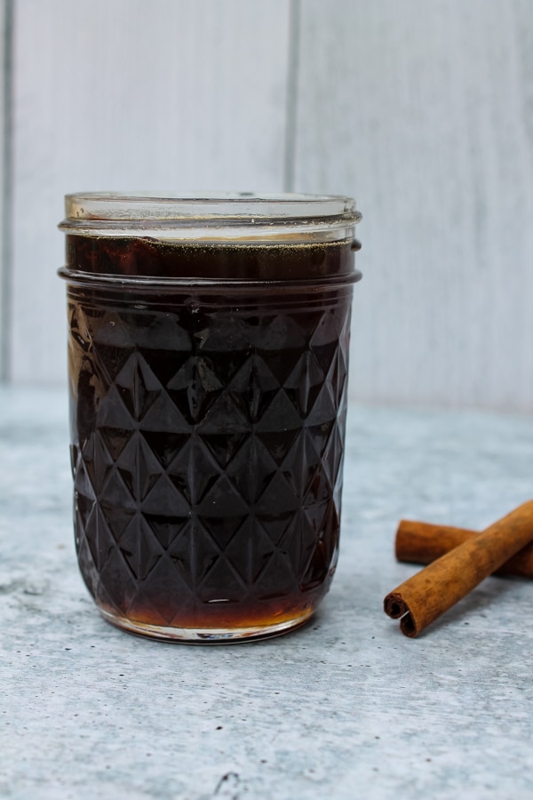 side view of a mason jar of Brown Sugar Cinnamon Simple Syrup with two cinnamon sticks