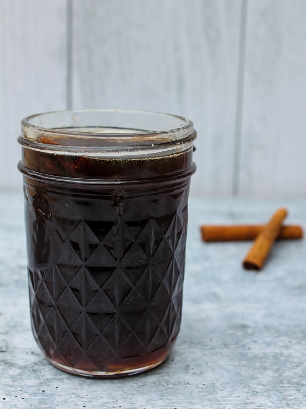 side view of a mason jar of Brown Sugar Cinnamon Simple Syrup with two cinnamon sticks