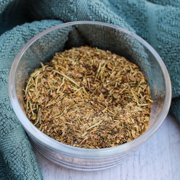 overhead view of a clear bowl of Greek Seasoning Spice Blend on a green and white background