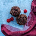 overhead view of two chocolate raspberry muffins on a clear plate