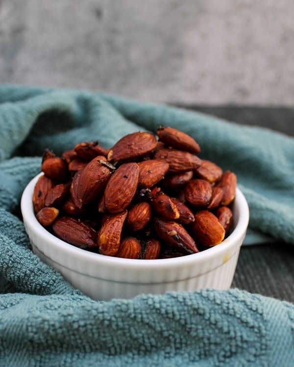 side view of honey and rosemary almonds in a small white bowl