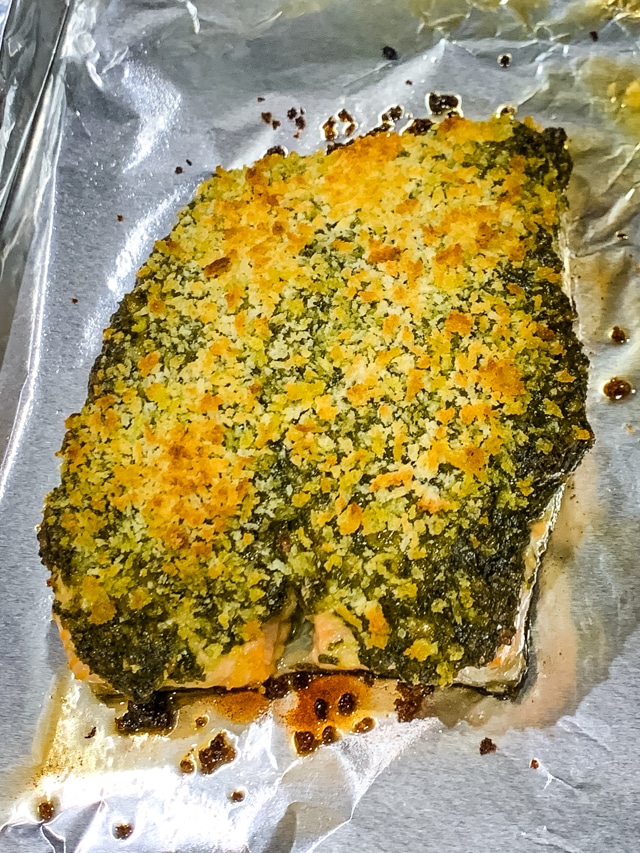 uncut pesto crusted salmon on a foil lined baking sheet