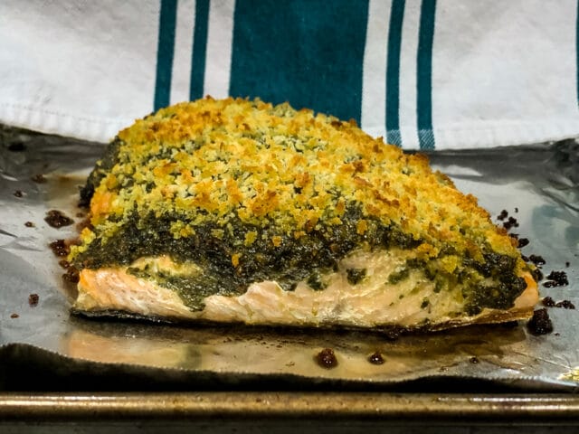 side view of pesto crusted salmon on a foil lined baking sheet