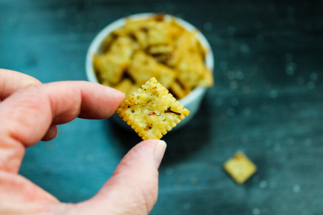 overhead view of a single spicy seasoned cracker, with the bowl of crackers in the background