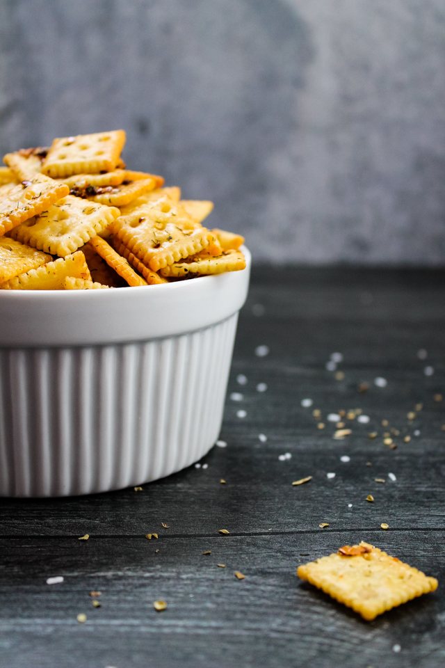 side view of a white bowl filled with spicy seasoned crackers