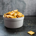 side view of a white bowl filled with spicy seasoned crackers