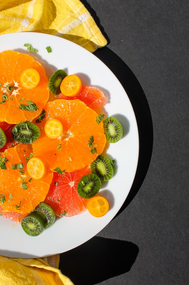 overhead view of citrus & mint fruit salad on a white plate