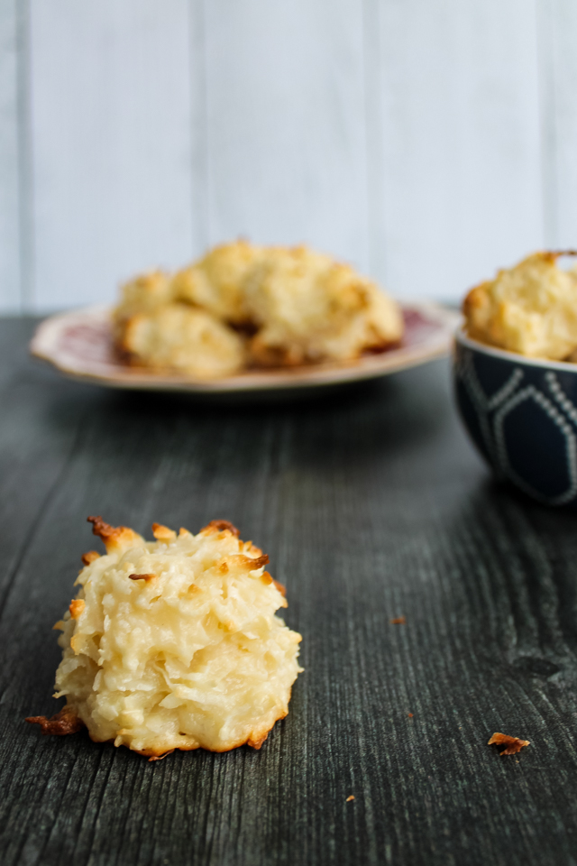 close up of a single coconut macaroon, with a plate of macaroons in the background