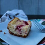 side view of a single raspberry cheesecake bar on a white plate