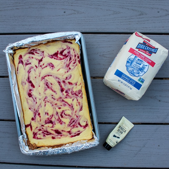 overhead view of a pan of raspberry cheesecake bars with sugar and vanilla paste