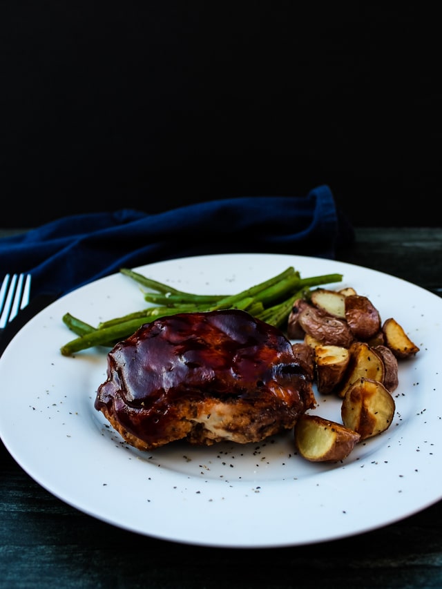 Side view of individual BBQ meatloaf, green beans and roasted potatoes on a white plate