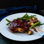 Side view of individual BBQ meatloaf, green beans and roasted potatoes on a white plate