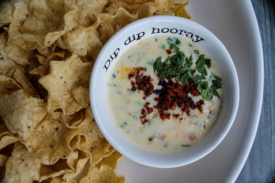 overhead view of queso topped with crumbled chorizo, amongst a plate of tortilla chips