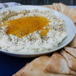 side view of Whipped Feta with Honey on a white plate, surrounded by pita slices