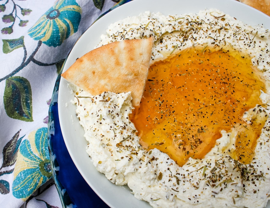 overhead view of Whipped Feta with Honey on a white plate, with a pita slice