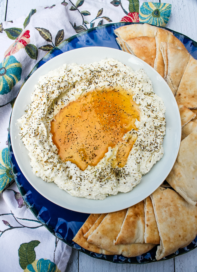 overhead view of Whipped Feta with Honey on a white plate, surrounded by pita slices